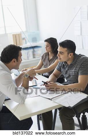 Stock Image - Hispanic business people working together in office. Fotosearch