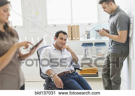 Stock Image - Hispanic businessman smiling in office. Fotosearch