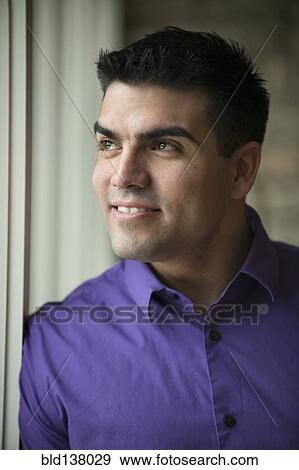 Hispanic businessman standing by window View Large Photo Image Stock Photo - Hispanic businessman standing by window. Fotosearch