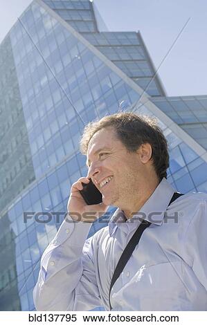 Hispanic businessman talking on cell phone on city street View Large Photo Image Stock Photography - Hispanic businessman talking on cell phone on city street. Fotosearch