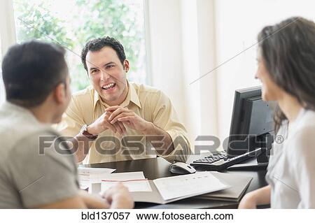 Stock Photo - Hispanic businessman talking to clients in office. Fotosearch