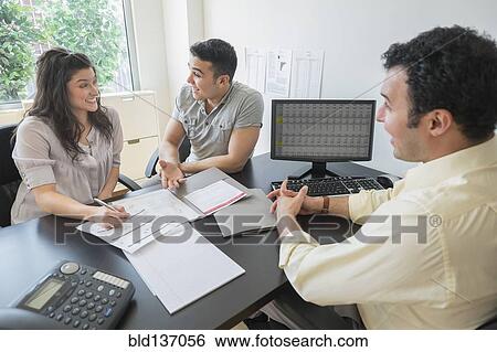 Stock Photograph - Hispanic businessman talking to clients in office. Fotosearch