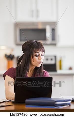 Stock Image - Hispanic businesswoman working at home. Fotosearch