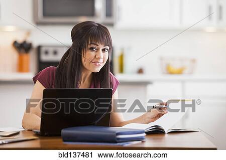 Stock Image - Hispanic businesswoman working at home. Fotosearch