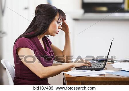 Stock Image - Hispanic businesswoman working at home. Fotosearch