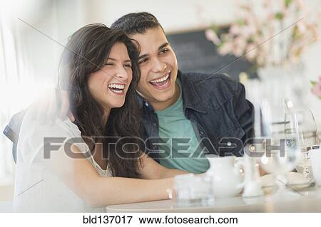 Stock Photo - Hispanic couple laughing in cafe. Fotosearch