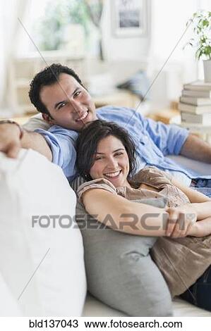 Stock Image - Hispanic couple relaxing together on sofa. Fotosearch