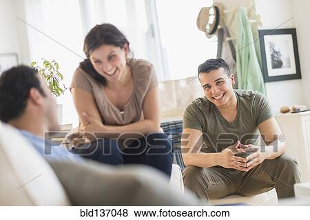 Stock Photo - Hispanic friends talking in living room. Fotosearch