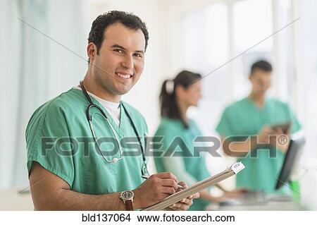 Picture - Hispanic nurse reading medical chart in hospital. Fotosearch