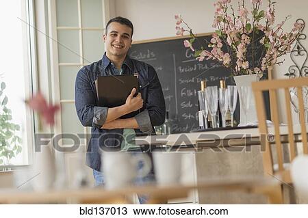 Stock Image - Hispanic waiter smiling in cafe. Fotosearch