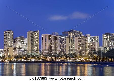 Stock Image - Illuminated city skyline on waterfront, Honolulu, Hawaii, United States. Fotosearch