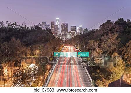 Stock Image - Los Angeles city skyline over busy highway illuminated at night, California, United States. Fotosearch