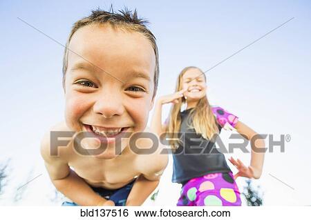 Stock Photograph - Low angle view of Caucasian children smiling outdoors. Fotosearch