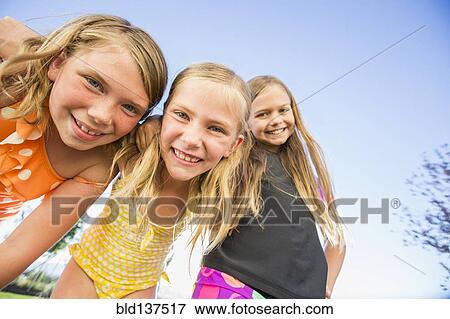 Stock Photo - Low angle view of Caucasian girls smiling outdoors. Fotosearch