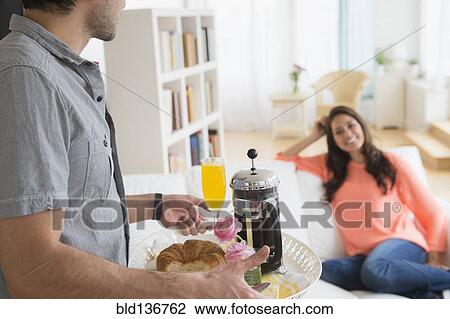 Man serving girlfriend breakfast on sofa View Large Photo Image Stock Image - Man serving girlfriend breakfast on sofa. Fotosearch