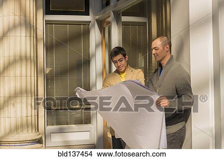 Picture - Men reading blueprints outdoors. Fotosearch