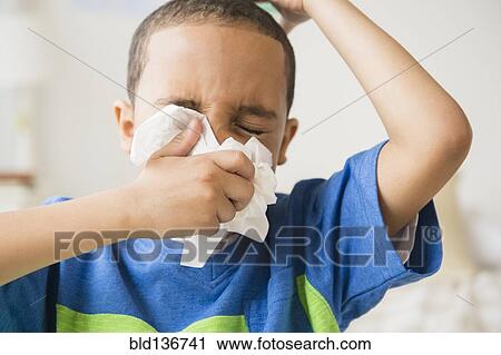 Stock Image - Mixed race boy blowing his nose. Fotosearch
