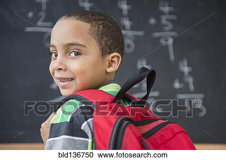 Stock Image - Mixed race boy doing math problems at board in class. Fotosearch