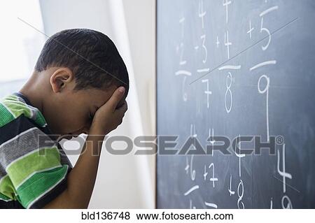 Stock Photo - Mixed race boy doing math problems at board in class. Fotosearch