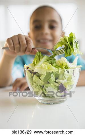 Stock Photo - Mixed race boy eating salad. Fotosearch