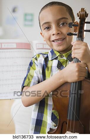 Stock Image - Mixed race boy holding violin. Fotosearch