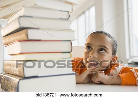 Mixed race boy looking up at stack of books View Large Photo Image Stock Image - Mixed race boy looking up at stack of books. Fotosearch