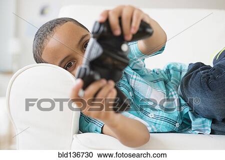 Stock Image - Mixed race boy playing video games. Fotosearch
