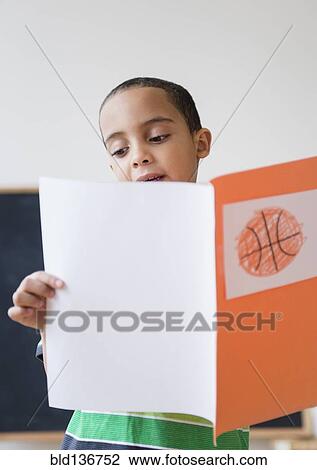 Stock Image - Mixed race boy reading report on basketball in class. Fotosearch