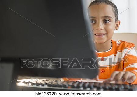 Stock Image - Mixed race boy using computer. Fotosearch