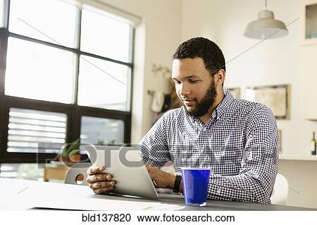 Stock Image - Mixed race businessman using tablet computer at desk. Fotosearch