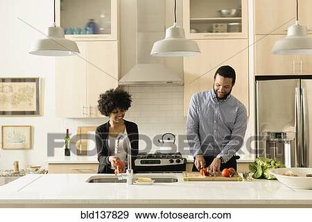 Stock Photo - Mixed race couple cooking together in kitchen. Fotosearch