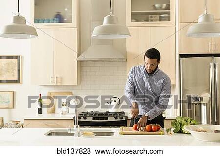 Stock Photo - Mixed race man cooking in kitchen. Fotosearch