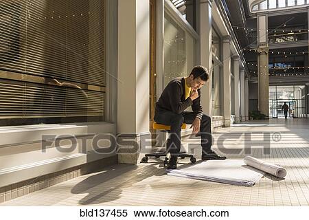 Stock Photography - Mixed race man reading blueprints in building. Fotosearch