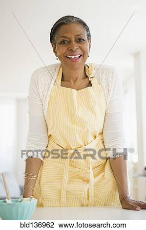 Stock Image - Mixed race woman cooking in kitchen. Fotosearch