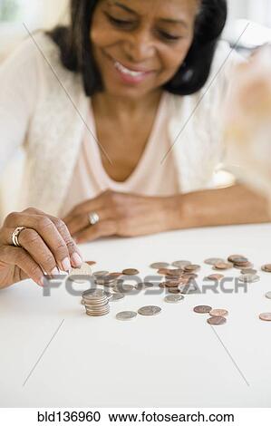 Stock Image - Mixed race woman counting change. Fotosearch