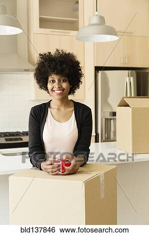 Stock Photograph - Mixed race woman drinking coffee in new house. Fotosearch