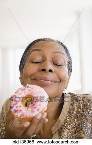 Stock Photo - Mixed race woman eating donut. Fotosearch
