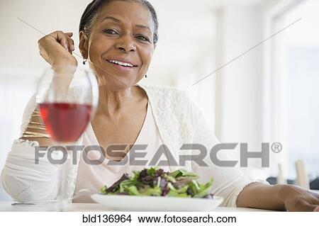 Mixed race woman eating salad at table View Large Photo Image Picture - Mixed race woman eating salad at table. Fotosearch