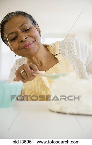 Mixed race woman frosting cake in kitchen View Large Photo Image Stock Image - Mixed race woman frosting cake in kitchen. Fotosearch