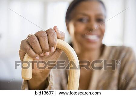 Stock Image - Mixed race woman holding cane. Fotosearch