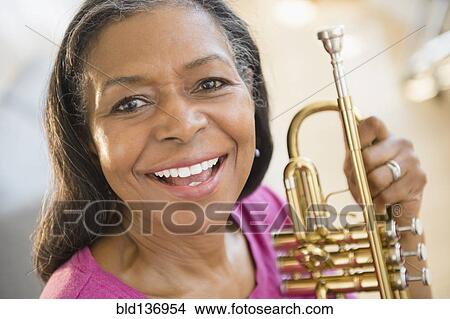 Picture - Mixed race woman holding trumpet. Fotosearch