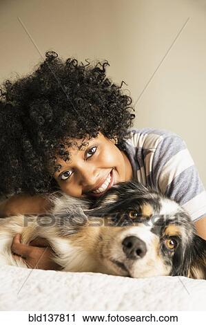 Mixed race woman laying with dog in bed View Large Photo Image Stock Image - Mixed race woman laying with dog in bed. Fotosearch