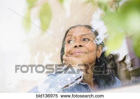 Stock Photography - Mixed race woman looking out window. Fotosearch