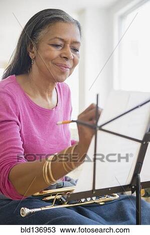 Stock Image - Mixed race woman playing trumpet. Fotosearch