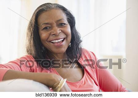 Stock Photo - Mixed race woman relaxing on sofa. Fotosearch