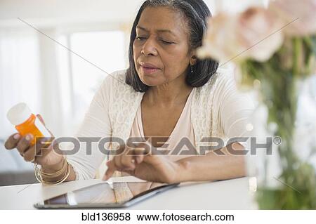 Stock Photo - Mixed race woman researching medication on tablet computer. Fotosearch