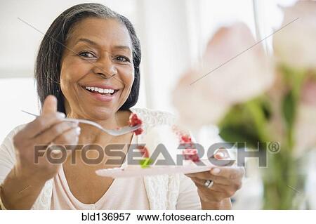 Stock Photo - Mixed race woman sharing cake . Fotosearch
