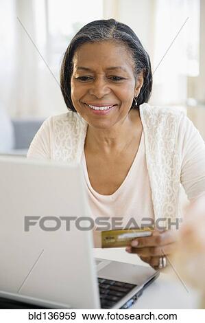 Stock Photo - Mixed race woman shopping on laptop. Fotosearch