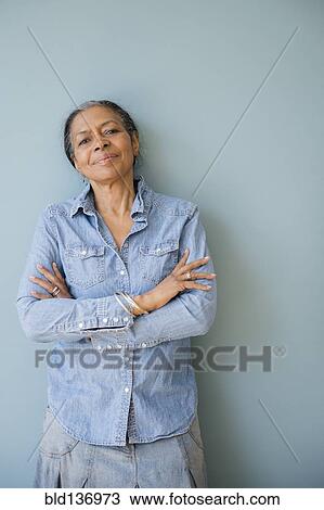 Stock Image - Mixed race woman standing with arms crossed. Fotosearch