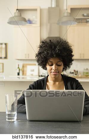 Mixed race woman using laptop at breakfast table View Large Photo Image Stock Photograph - Mixed race woman using laptop at breakfast table. Fotosearch